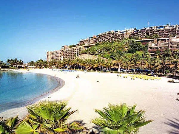La playa de Anfi del Mar con las palmeras y los apartamentos detrás
